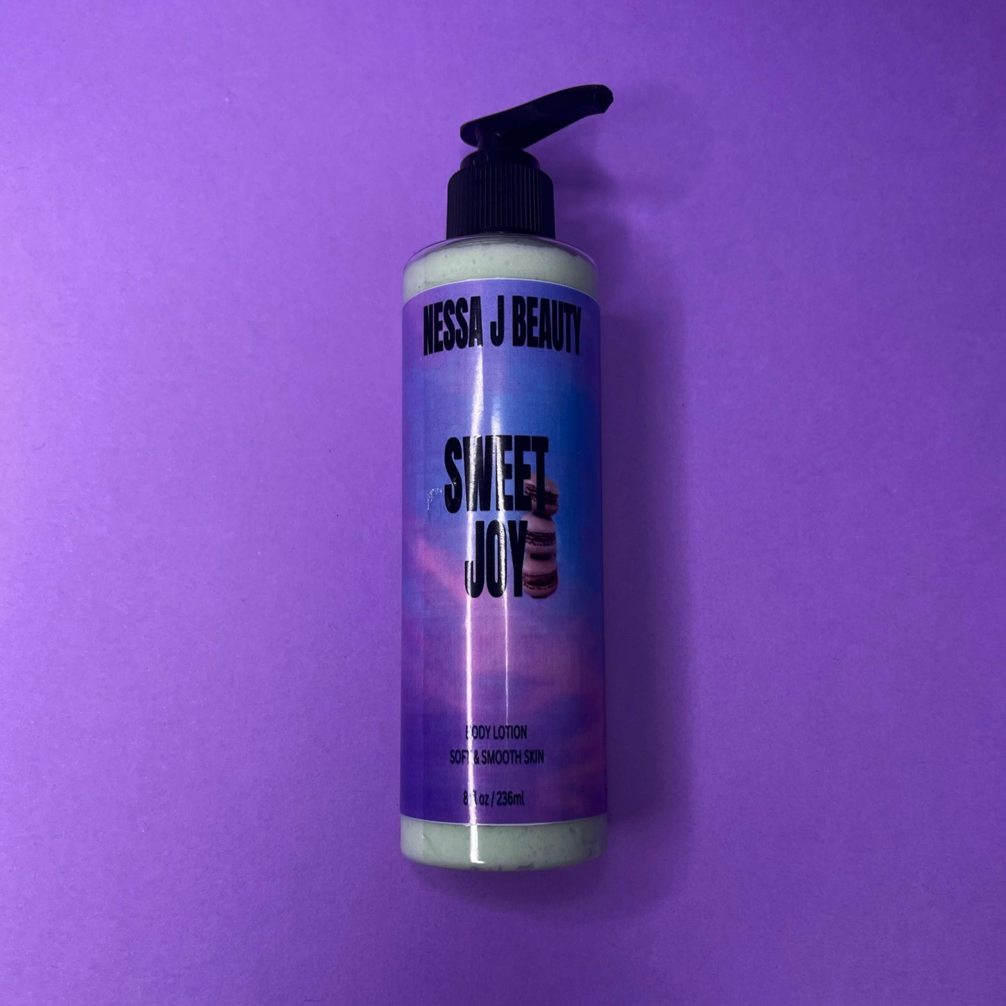 Bottle of Nessa J Beauty Sweet Joy lotion on a purple background