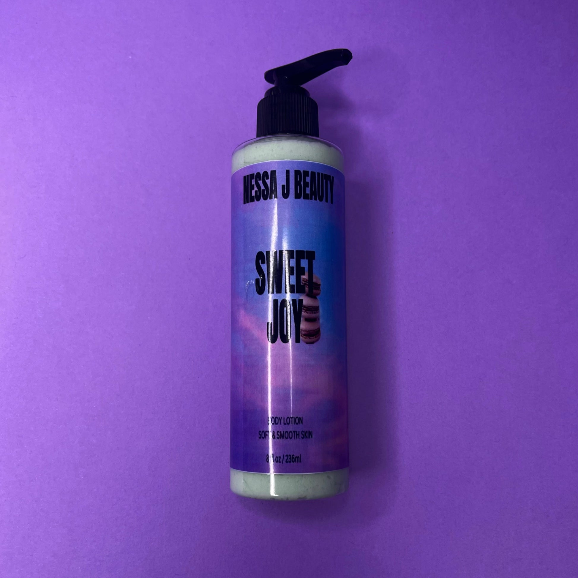 Bottle of Nessa J Beauty Sweet Joy lotion on a purple background